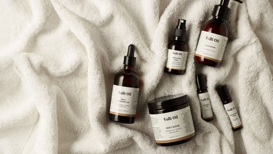Flat lay of Folli Oil’s natural skincare range, including exfoliating and hydrating treatments, displayed on a white towel — essentials for preventing ingrown hairs, redness, and irritation naturally.
