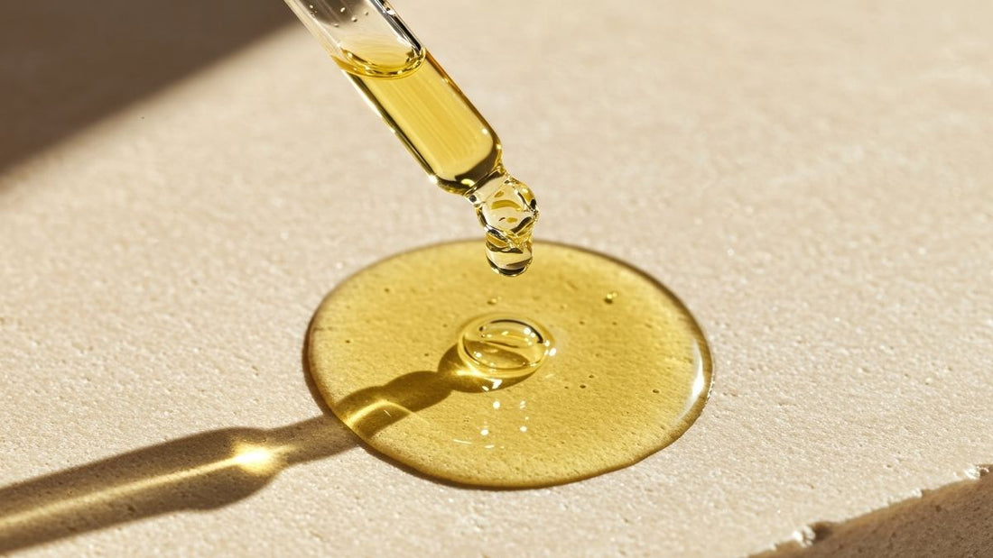 A pool of golden oil spreading from a dropper onto a neutral plate, symbolising natural skincare, hydration, and plant-based healing.