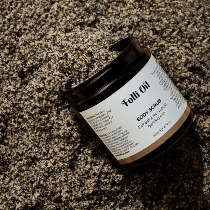 Top-down view of body scrub jar with lid off, resting on spread-out product, highlighting exfoliating texture.